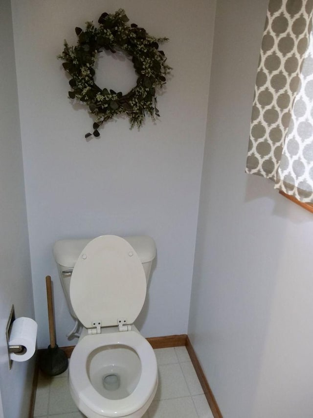 bathroom with toilet, baseboards, and tile patterned floors