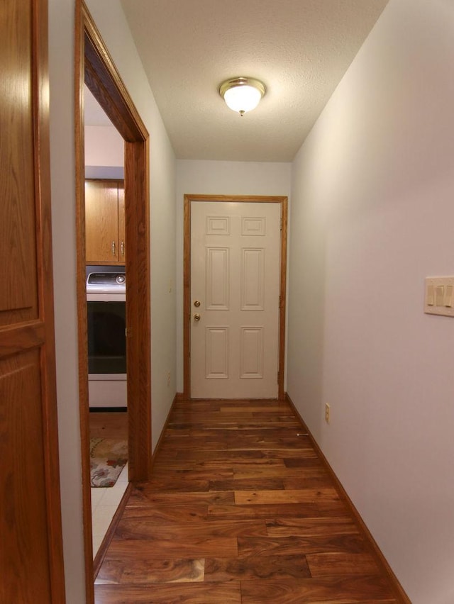 hall featuring washer / dryer, a textured ceiling, and dark wood-style flooring