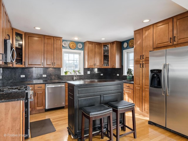 kitchen with glass insert cabinets, appliances with stainless steel finishes, a breakfast bar, and a wealth of natural light