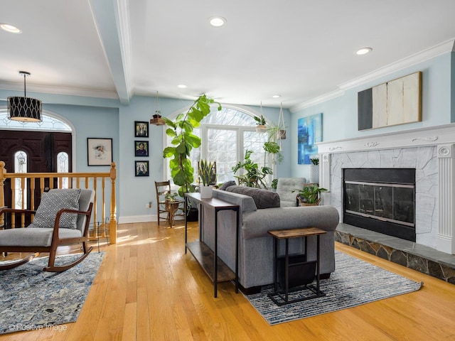 living area with a fireplace, crown molding, recessed lighting, light wood-style flooring, and baseboards