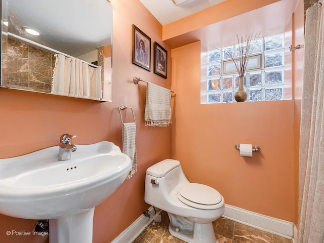 full bathroom with curtained shower, baseboards, a sink, and toilet