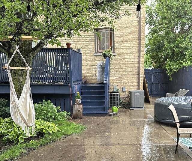 view of property exterior featuring a patio, central AC, brick siding, fence, and stairs