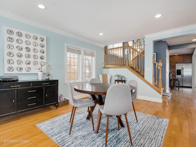 dining room with ornamental molding and light wood-style flooring