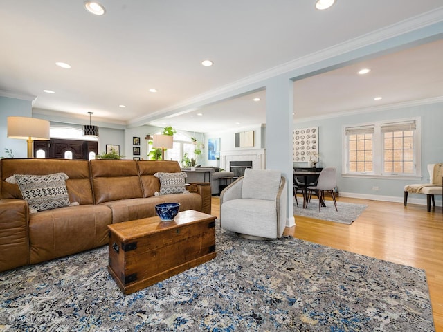 living area featuring ornamental molding, wood finished floors, a glass covered fireplace, and recessed lighting