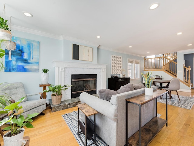 living room featuring stairs, wood finished floors, a high end fireplace, and crown molding