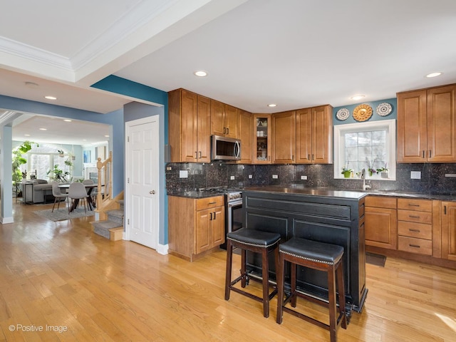 kitchen with appliances with stainless steel finishes, a kitchen bar, glass insert cabinets, and brown cabinets