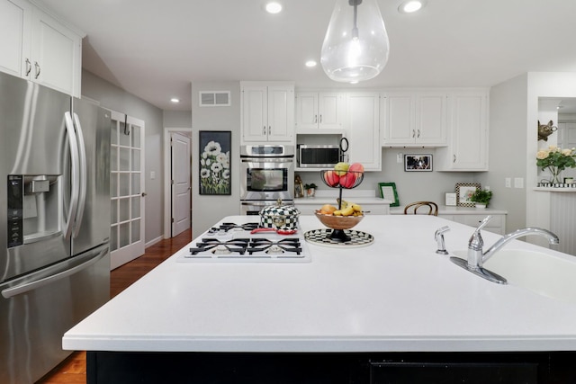 kitchen featuring stainless steel appliances, a center island, light countertops, and visible vents