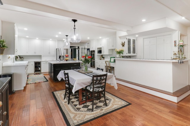 dining room with recessed lighting, beverage cooler, and light wood-style flooring