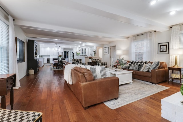 living area featuring beam ceiling, wood-type flooring, and an inviting chandelier