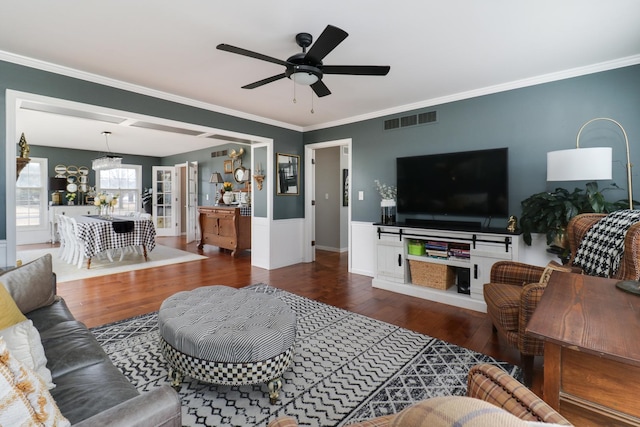 living area with visible vents, wood finished floors, and ornamental molding