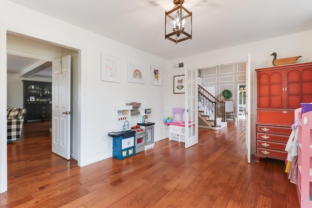 game room featuring a notable chandelier, wood-type flooring, visible vents, and baseboards