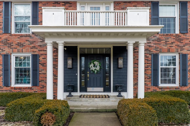 entrance to property featuring brick siding and a balcony