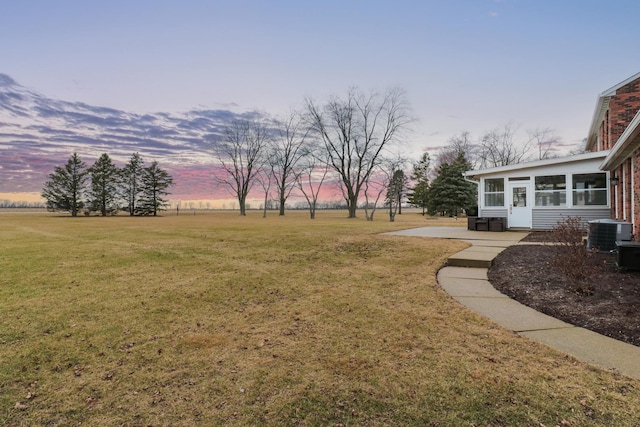 view of yard featuring a sunroom and central AC unit