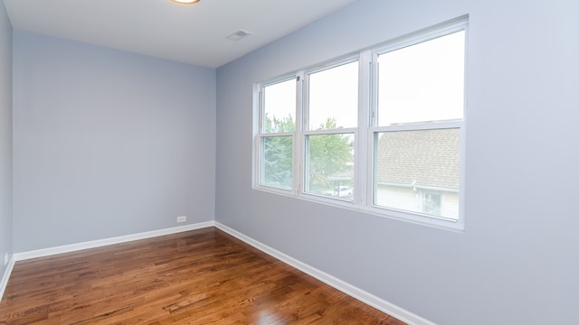 spare room with visible vents, baseboards, and dark wood-style flooring