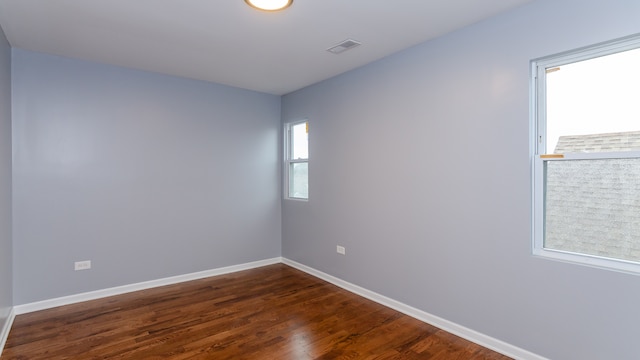 spare room with visible vents, dark wood finished floors, and baseboards