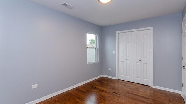 unfurnished bedroom with baseboards, a closet, visible vents, and dark wood-style flooring