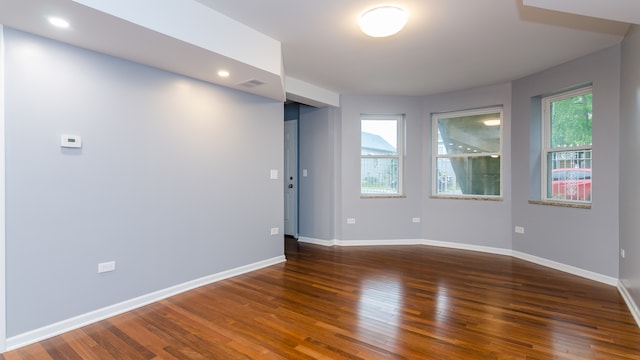 unfurnished room with plenty of natural light, baseboards, and dark wood-type flooring