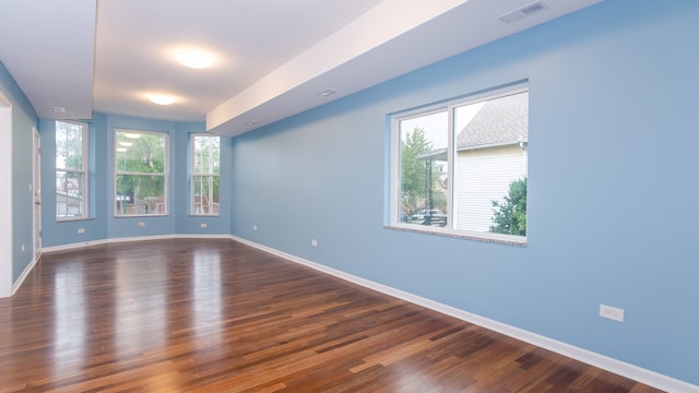 unfurnished room featuring dark wood finished floors, visible vents, and baseboards