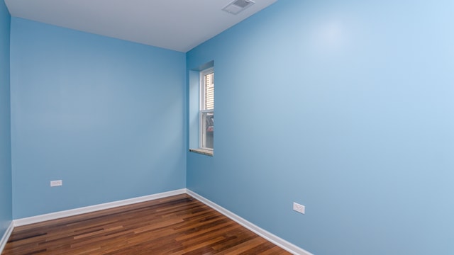 spare room featuring dark wood-style floors, visible vents, and baseboards