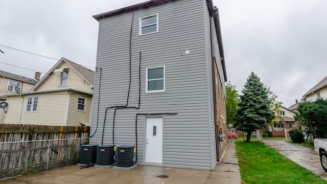 back of house with central AC and fence