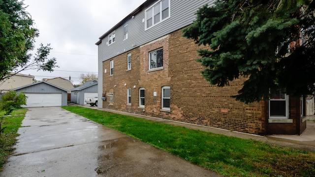 view of side of property featuring a garage, brick siding, and an outdoor structure