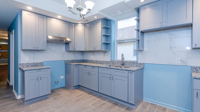 kitchen with open shelves, tasteful backsplash, a sink, and under cabinet range hood