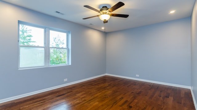 empty room featuring dark wood-style floors, visible vents, ceiling fan, and baseboards