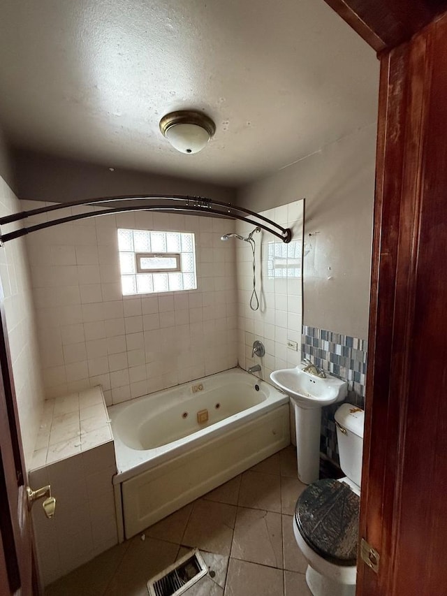 bathroom with tile patterned flooring, toilet, visible vents, tile walls, and a combined bath / shower with jetted tub