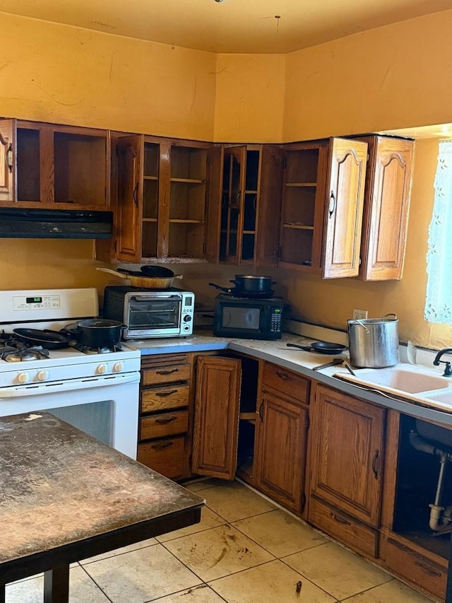 kitchen with white gas stove, under cabinet range hood, open shelves, and a toaster