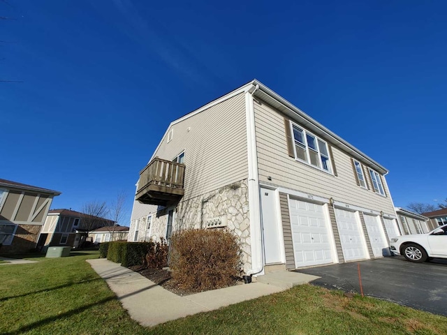 view of home's exterior featuring a garage, a yard, and a balcony