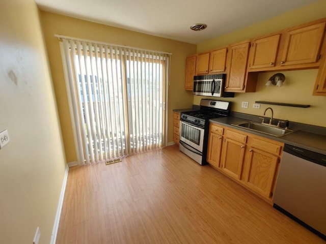 kitchen with a sink, visible vents, baseboards, appliances with stainless steel finishes, and light wood finished floors