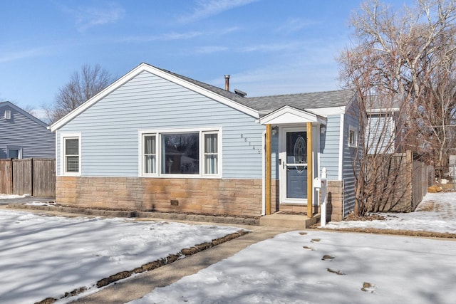 view of front of home with stone siding, roof with shingles, and fence