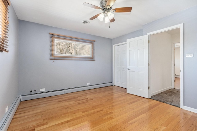 unfurnished bedroom featuring light wood-type flooring, a closet, visible vents, and baseboard heating