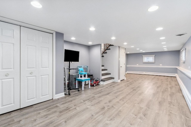 below grade area featuring a baseboard heating unit, stairway, recessed lighting, and light wood-style floors