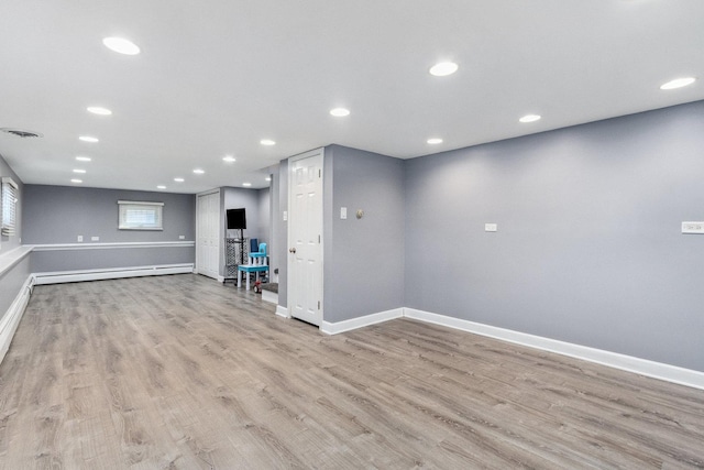 unfurnished living room featuring a baseboard heating unit, baseboards, visible vents, and light wood-style floors