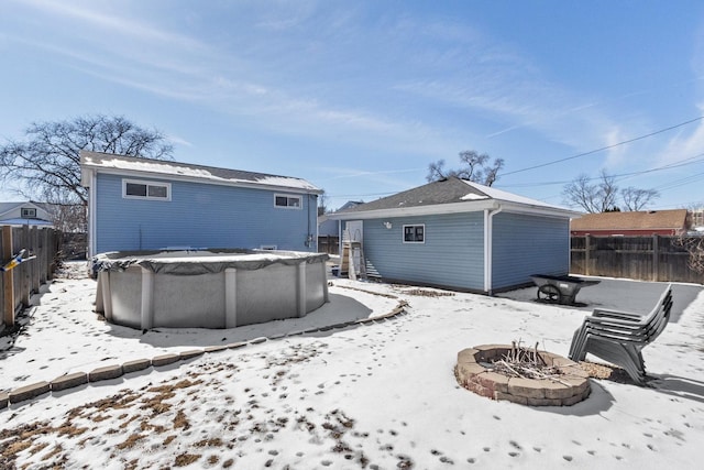 snow covered property featuring a fenced in pool, fence, and a fire pit