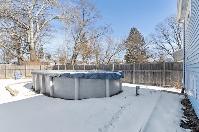 snowy yard with a fenced backyard and a fenced in pool