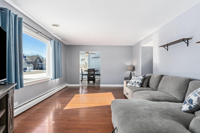 living area featuring dark wood-type flooring, a baseboard radiator, visible vents, and baseboards