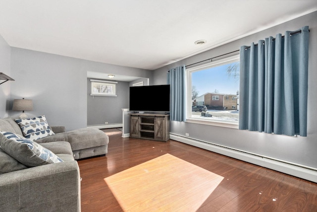 living room with a baseboard heating unit, dark wood-type flooring, visible vents, and baseboards