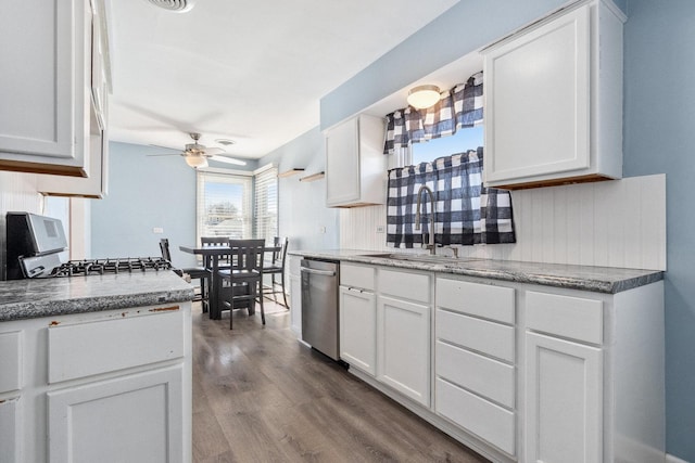 kitchen with white cabinets, a sink, stainless steel dishwasher, and wood finished floors