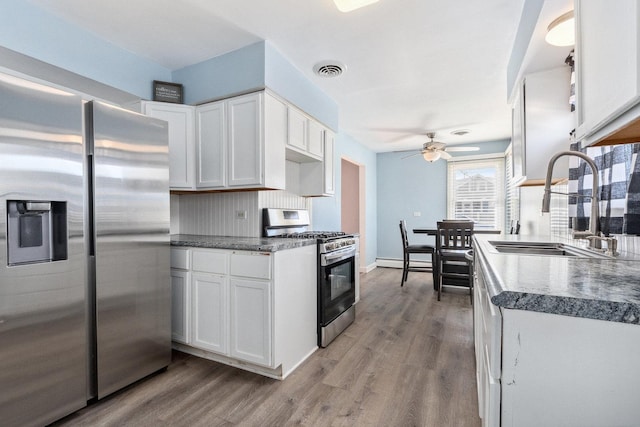 kitchen featuring stainless steel appliances, dark countertops, and white cabinetry