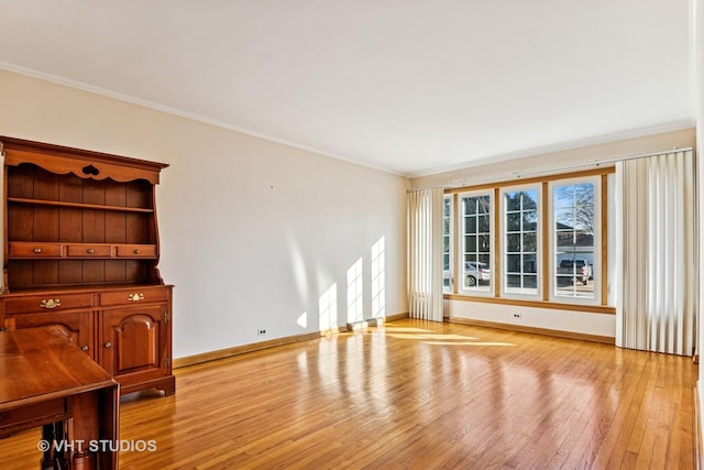 unfurnished living room with light wood-style floors, baseboards, and crown molding