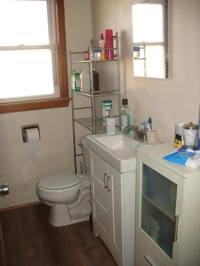 half bathroom featuring toilet, wood finished floors, and vanity