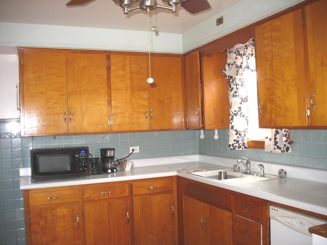 kitchen featuring black microwave, a sink, light countertops, brown cabinets, and dishwasher