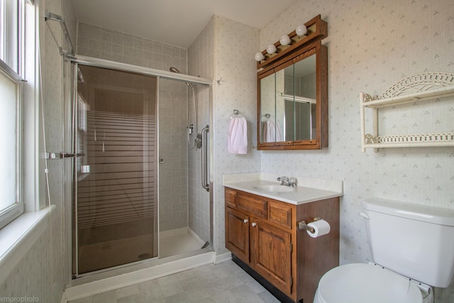 bathroom featuring toilet, vanity, wallpapered walls, and a shower stall