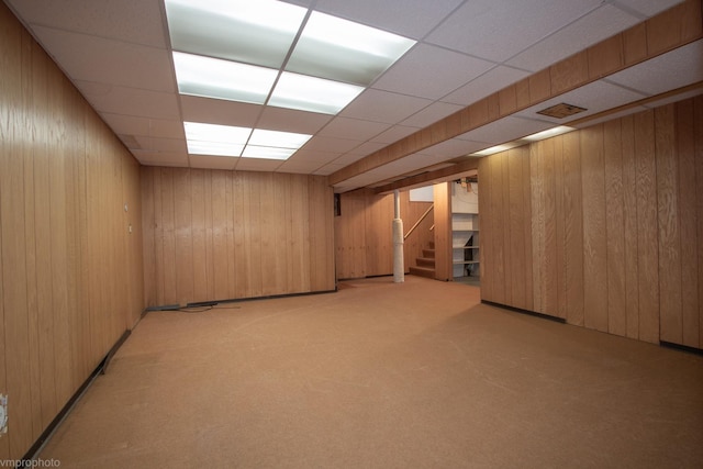 finished below grade area with stairway, light colored carpet, and wood walls