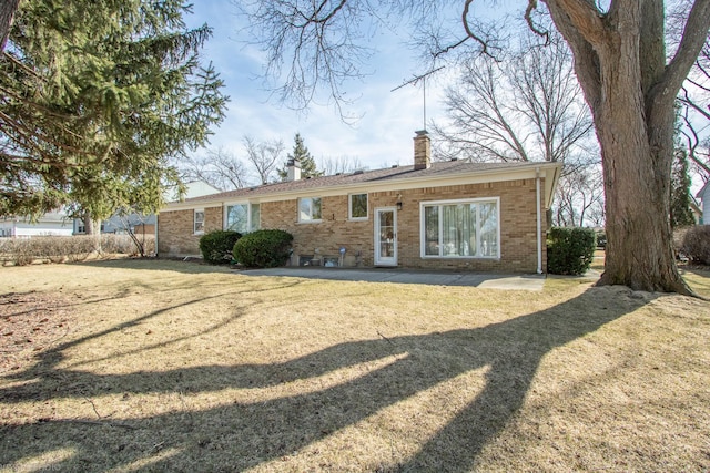 view of front of property featuring a front lawn, brick siding, and a chimney