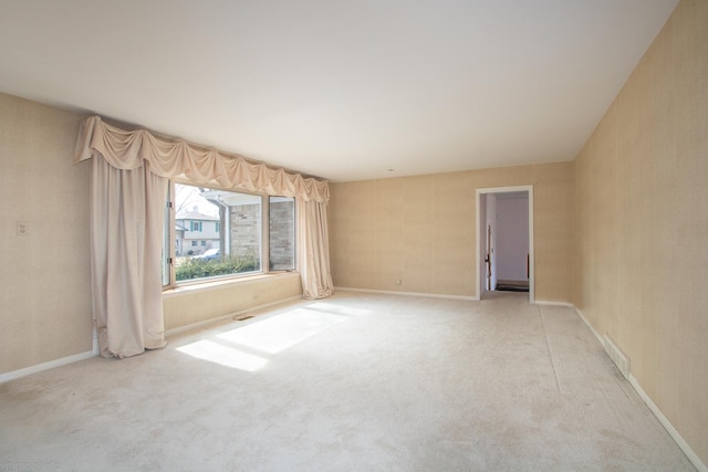 spare room featuring baseboards, visible vents, and light carpet