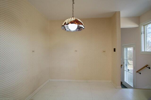 unfurnished dining area with wallpapered walls and baseboards