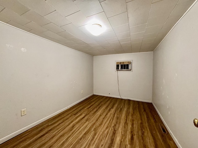 basement with visible vents, baseboards, and dark wood finished floors